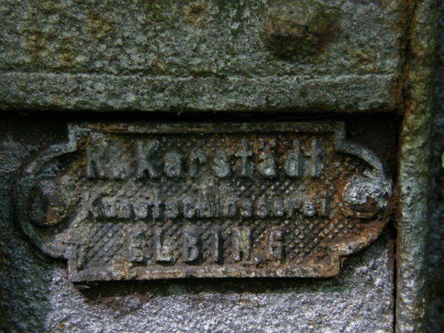 Tabliczka elbląskiego producenta ogrodzenia cmentarnego przy ul. Sadowej (Czerwiec 2008)